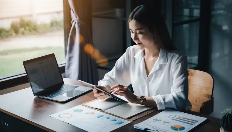 Geschäftsinhaber kalkuliert SEO-Budget am Schreibtisch mit Laptop und Notizen